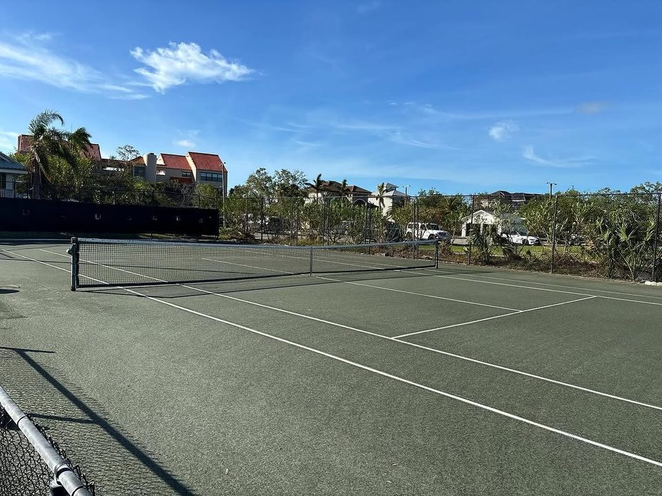 A clay court mid-refurbishment under a clear Florida sky.